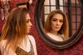 Portrait of a beautiful young woman standing near the mirror looking at his reflection Royalty Free Stock Photo