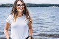 Portrait of a beautiful young woman in stylish glasses. Girl in white tshirt posing on the background of the lake landscape Royalty Free Stock Photo