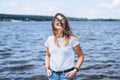 Portrait of a beautiful young woman in stylish glasses. Girl in white tshirt posing on the background of the lake landscape Royalty Free Stock Photo