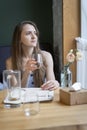 Portrait of beautiful young woman in summer sundress in a restaurant. Girl enjoys wonderful day at table in cafe Royalty Free Stock Photo