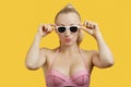 Portrait of a beautiful young woman in sunglasses puckering lips over yellow background