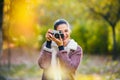 Portrait of beautiful young woman taking photos with vintage camera outdoors in the nature Royalty Free Stock Photo