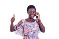 Beautiful young woman talking on the mobile phone and showing her thumb while smiling Royalty Free Stock Photo