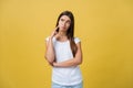 Portrait of a beautiful young woman thinking, isolated on yellow background Royalty Free Stock Photo