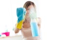 Beautiful young woman using a duster and a spray and smiling while cleaning windows at home. Royalty Free Stock Photo