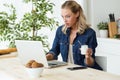 Beautiful young woman using her laptop and eating yogurt at home Royalty Free Stock Photo