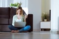 Beautiful young woman using her laptop for shopping online at home. Royalty Free Stock Photo