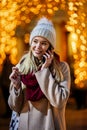 Portrait of beautiful young woman using her mobile phone in the street with christmas decoration. Royalty Free Stock Photo