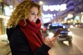 Beautiful young woman using her mobile phone in the street at night. Royalty Free Stock Photo