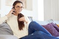 Lovely young woman talking with somebody on her mobile phone while sitting on sofa at home Royalty Free Stock Photo