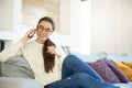 Lovely young woman talking with somebody on her mobile phone while sitting on sofa at home Royalty Free Stock Photo