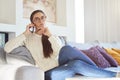 Lovely young woman talking with somebody on her mobile phone while sitting on sofa at home Royalty Free Stock Photo