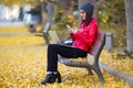 Beautiful young woman using her mobile phone while working with laptop in autumn. Royalty Free Stock Photo