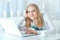 Beautiful young woman using laptop while sitting at kitchen table Royalty Free Stock Photo