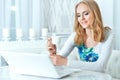 Beautiful young woman using laptop while sitting at kitchen table Royalty Free Stock Photo
