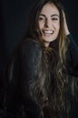 Portrait of a beautiful young woman with very long hair laughing merrily and with one hand on her head Royalty Free Stock Photo