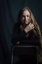 Portrait of a beautiful young woman with very long hair who is smiling sitting on a stool Royalty Free Stock Photo