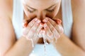 Beautiful young woman washing her face splashing water in a home bathroom.