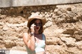 Portrait of a beautiful young woman wearing a hat and sunglasses against the backdrop of a ruined building. The woman`s lips are