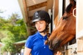 Beautiful young horsewoman standing by bay horse Royalty Free Stock Photo