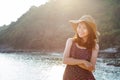 portrait of beautiful young woman wearing wide straw hat standing beside sea beach and toothy smiling face wtih happy emotion Royalty Free Stock Photo