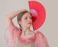 Portrait of a beautiful young woman on a white background dancing flamenco. A hand with a red fan is raised up