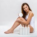 Portrait of a beautiful young woman in a white bathing suit with a body cream in her hands. Body care Royalty Free Stock Photo