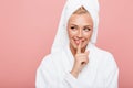 Portrait of beautiful young woman wrapped in white towel after shower smiling and holding finger at her lips Royalty Free Stock Photo