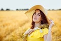 Portrait of a beautiful young woman in a yellow dress with a straw hat on a Golden wheat field at sunset. Sensual girl is enjoying Royalty Free Stock Photo