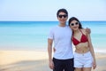 Portrait of beautiful young women and boyfriend asian, wearing rea bikini and stylish white sunglasses standing on the seashore