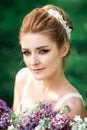Portrait of beauty bride in white dress. The bride is holding a wedding bouquet of lilacs. Royalty Free Stock Photo