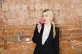 Portrait of beauty business woman with lolipop and santa hat wearing. Brick red background. Royalty Free Stock Photo