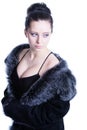 Beautiful brunette with decollete in luxury black color fur coat looking away