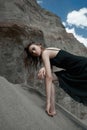 Portrait of a beauty fashion woman in the branches of a dead tree. Girl on the background of sand mountains