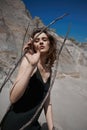 Portrait of a beauty fashion woman in the branches of a dead tree. Girl on the background of sand mountains