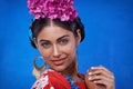 Portrait, beauty and happy woman with flowers in hair isolated on blue studio background in India. Face, smile or person Royalty Free Stock Photo