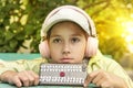 Portrait of beauty kid girl with long brunette hair wearing white cap with headphones listening to music outside. child Royalty Free Stock Photo