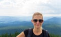 Portrait of beauty young caucasian woman with sunglasses and backpack standing on lookout Boubin, nature reserve Sumava