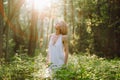 Portrait of becalmed woman standing in forest among plants trees on sunny day, luxuriating in warm sunshine, looking up. Royalty Free Stock Photo