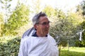 PORTRAIT OF AN ELDERLY BEEKEEPER SMILING AFTER WORK, ON A GREEN BACKGROUND Royalty Free Stock Photo