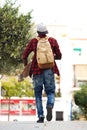 Behind of young man walking outdoors with bag and skateboard Royalty Free Stock Photo