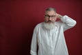 Portrait of bewildered mature caucasian bearded man dressed white shirt over red background, selective focus Royalty Free Stock Photo