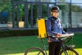 Portrait of bicycle courier with yellow bag and bike. Man in helmet and glasses holding pizza box Royalty Free Stock Photo