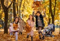 portrait of big family in autumn city park, children running with armful of leaves, happy people playing together and scattering