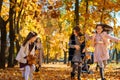 portrait of big family in autumn city park, children running with armful of leaves, happy people playing together and scattering