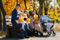 Portrait of big family with children in an autumn city park, happy people sitting together on a wooden bench, posing and smiling, Royalty Free Stock Photo