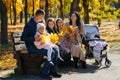 portrait of big family with children in an autumn city park, happy people sitting together on a wooden bench, posing and smiling, Royalty Free Stock Photo