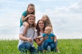 Portrait big family dad, mom and three children on green grass against blue sky. Happy caucasian parents, two daughters Royalty Free Stock Photo