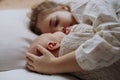 Portrait of big sister cuddling newborn, little baby. Girl lying with her new sibling in bed, closed eyes. Sisterly love