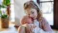 Portrait of big sister soothing newborn sister. Girl taking care of crying baby. Sisterly love, joy for new family Royalty Free Stock Photo